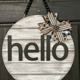 Hello Door Hanger is shown hanging on a front door. This is the white distressed hanger with black beaded garland.