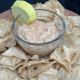 Dip in a glass bowl surrounded by tortilla chips on a wooden board.