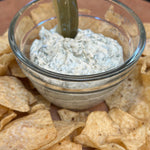 Glass bowl of dip with tortilla chips on a wooden surface
