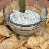 Glass bowl of dip with tortilla chips on a wooden surface