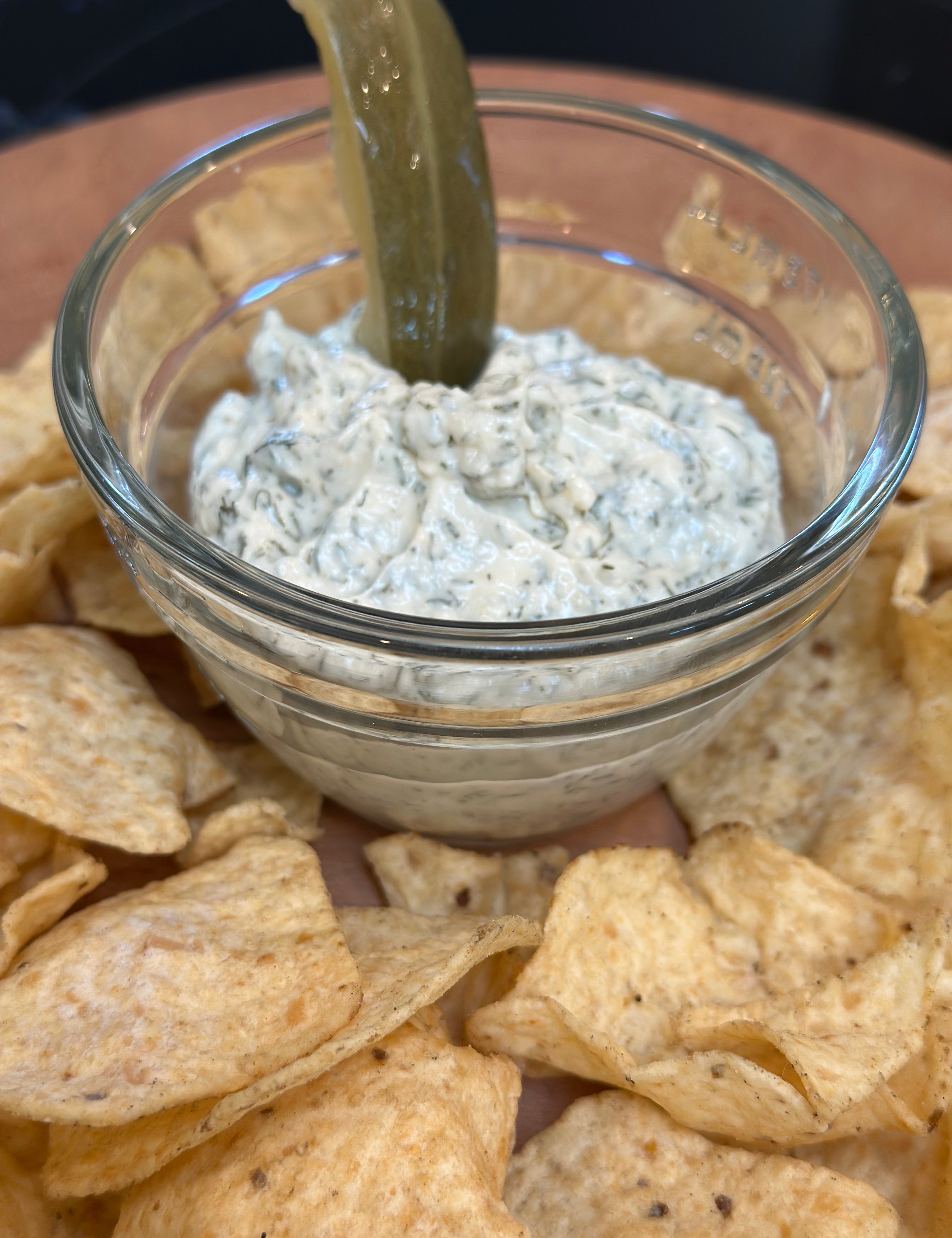 Glass bowl of dip with tortilla chips on a wooden surface