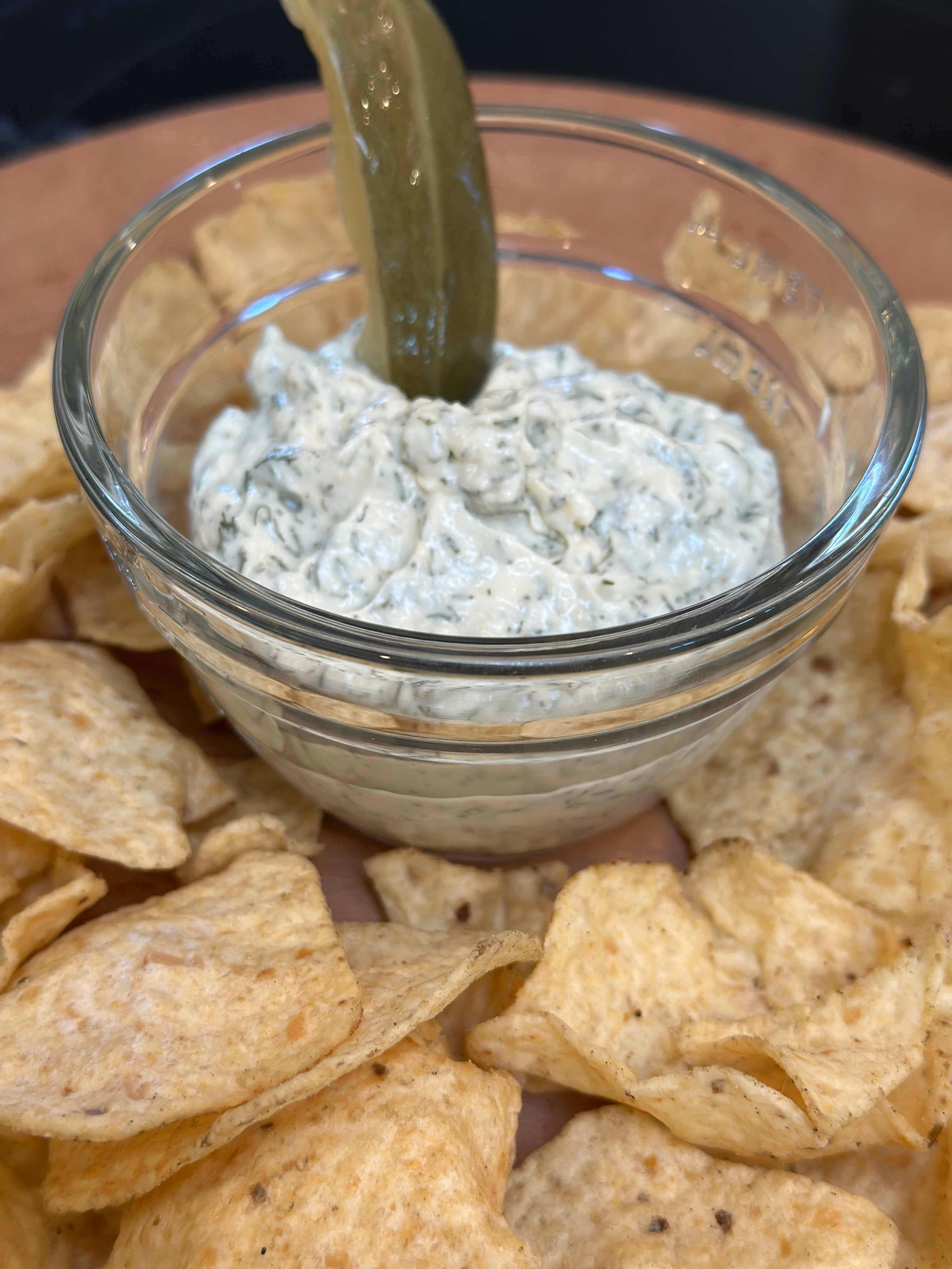 Glass bowl of dip with tortilla chips on a wooden surface