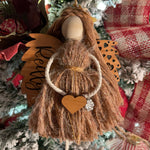This image shows the angel hanging on a Christmas tree with the engraved name Reilly. The angel is holding a wooden heart and has a paw charm on the arm.