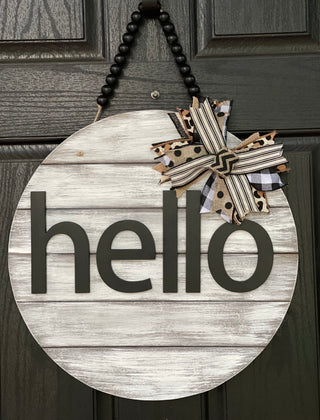 Hello Door Hanger is shown hanging on a front door.  This is the white distressed hanger with black beaded garland.