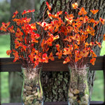 Bittersweet Floral Glass Vase shows an image of two vases together.  Each vase has tricolored earth tone rocks and tan moss with orange bittersweet artificial floral decor. Each sold separately.  