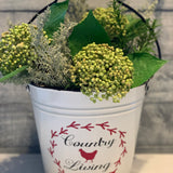 Country Living White Metal Pail is shown with a floral arrangement.  Flowers are not sold with bucket.