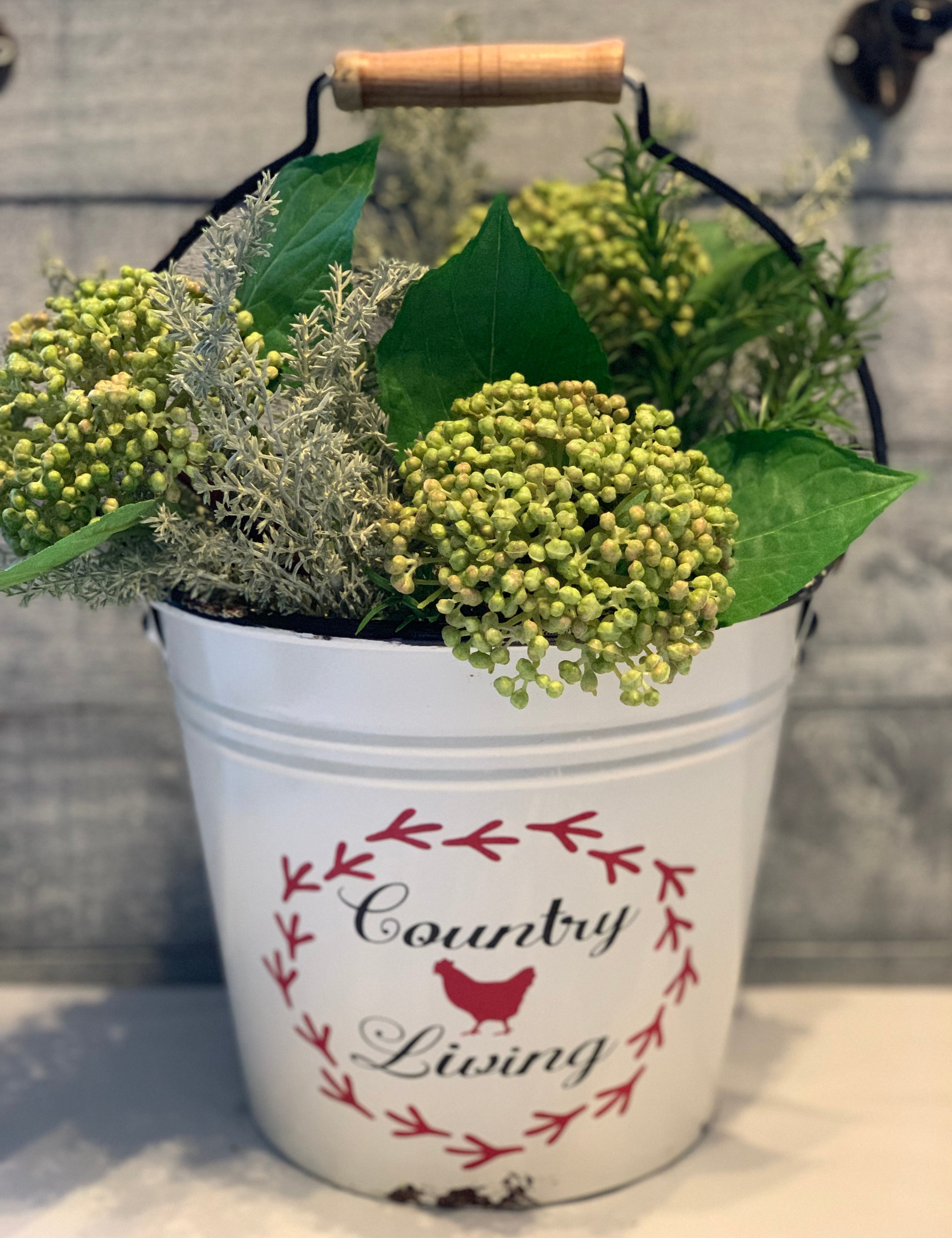 Country Living White Metal Pail is shown with a floral arrangement.  Flowers are not sold with bucket.