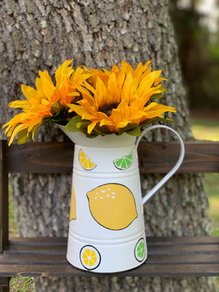 White Metal Lemon and Lime Pitcher shows an image of the pitcher with sunflowers sitting on a ladder outside.