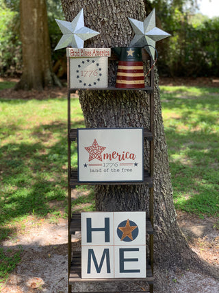 Primitive Red, Tan, and Navy Metal Pitcher is shown with the primitive home sign, the July sign of the month, the metal stars, and the 1776 sign.  Each item is sold separately.