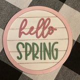 Hello Spring round 5" shiplap sign is shown laying on a table.