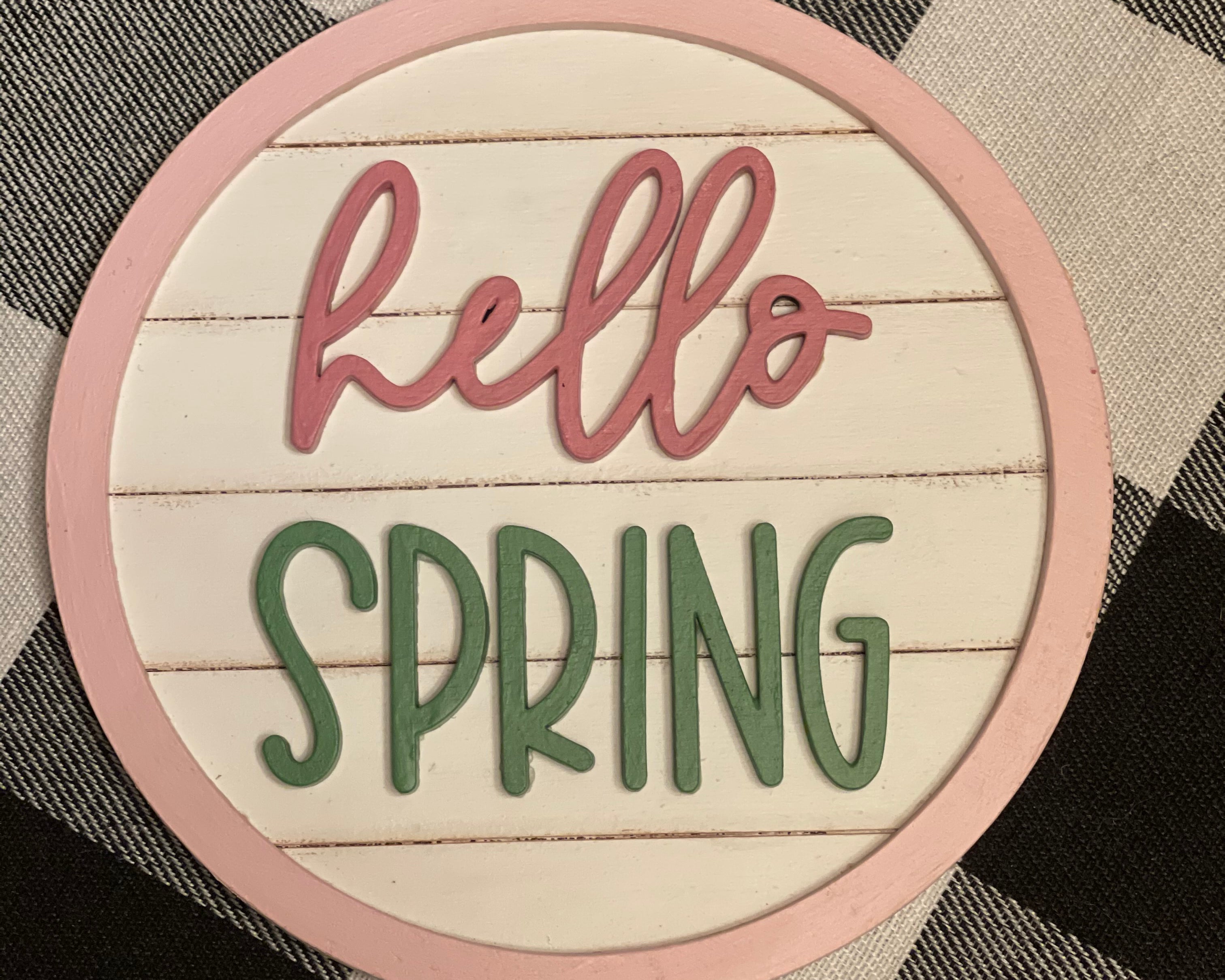 Hello Spring round 5" shiplap sign is shown laying on a table.
