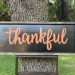 Metallic Thankful Sign shows an image of the sign sitting on a ladder outside.