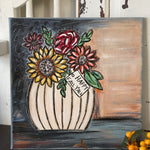 This image shows the hand painted sign displayed on a bench with fall floral flowers.