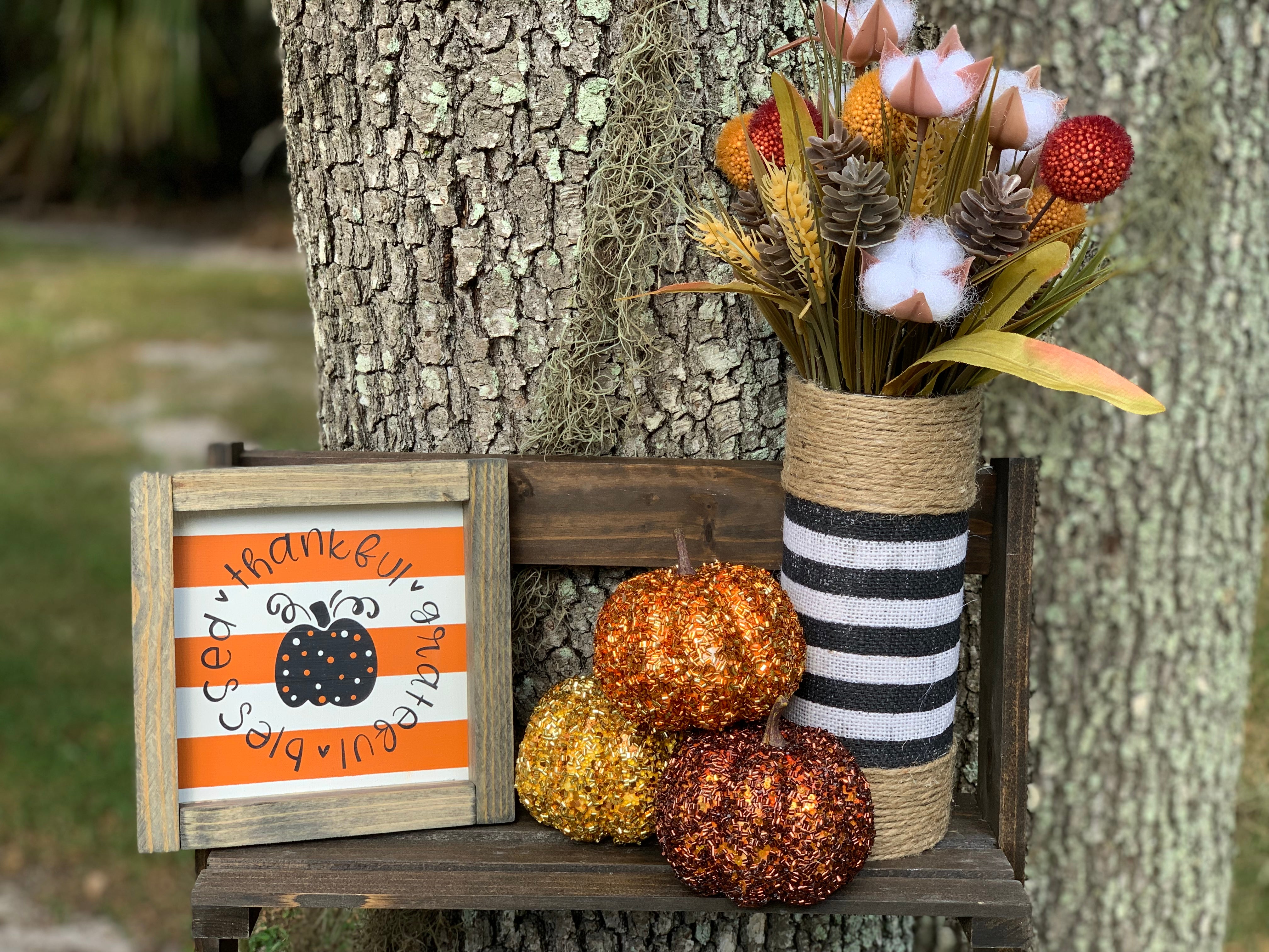 Orange and White Stripe Thankful, Grateful, Blessed (Pumpkin) shows a picture of the sign sitting outside with the black and white stripe burlap vase and pumpkin and floral embellishments.  Items are each sold separately. Pumpkins not eligible for purchase.