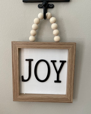 This image shows the JOY sign hanging on a hook.