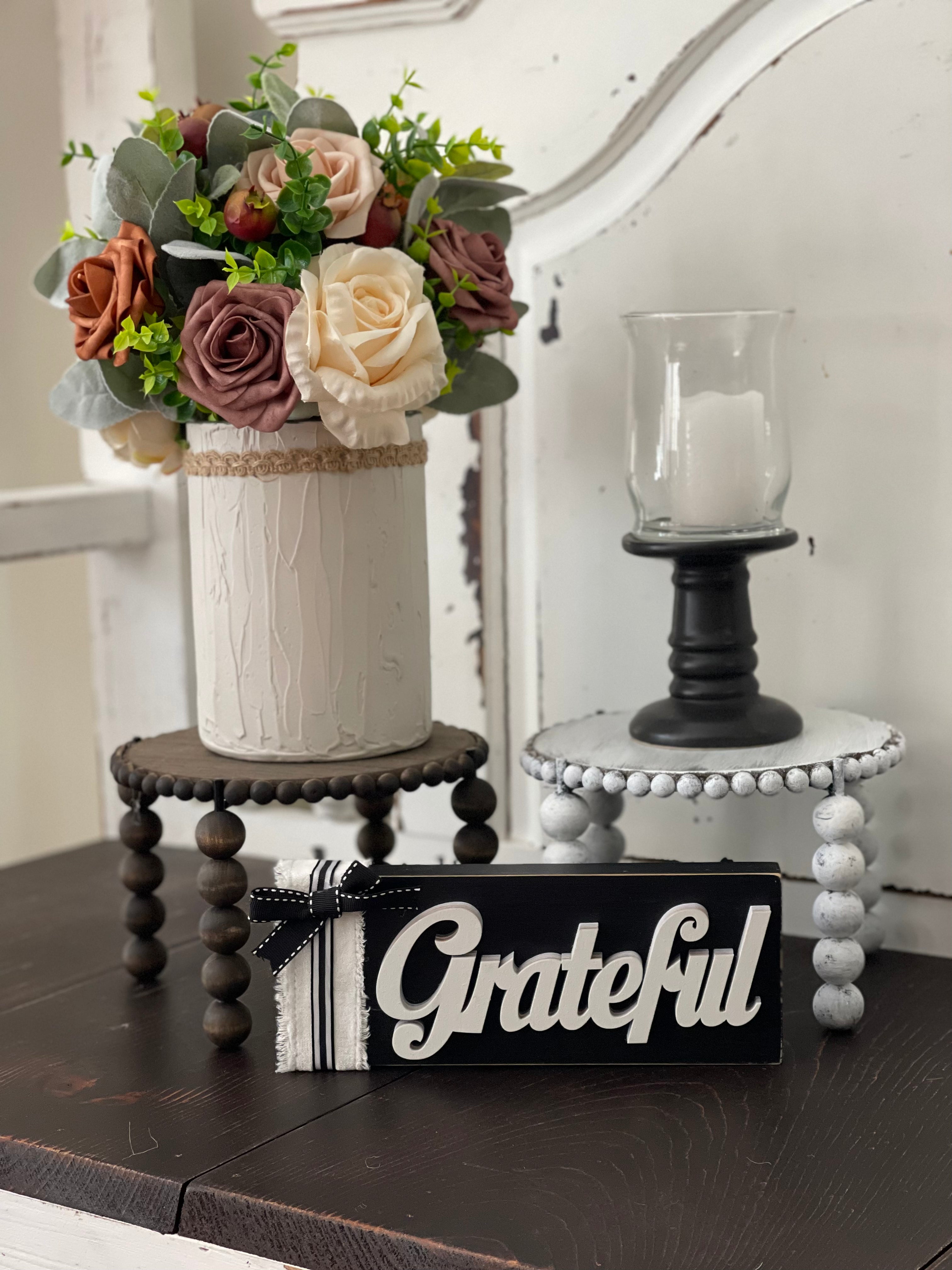 This image shows the paired Jacobean and distressed white risers on a bench with a floral arrangement, candle and a grateful sign. Each item sold separately.