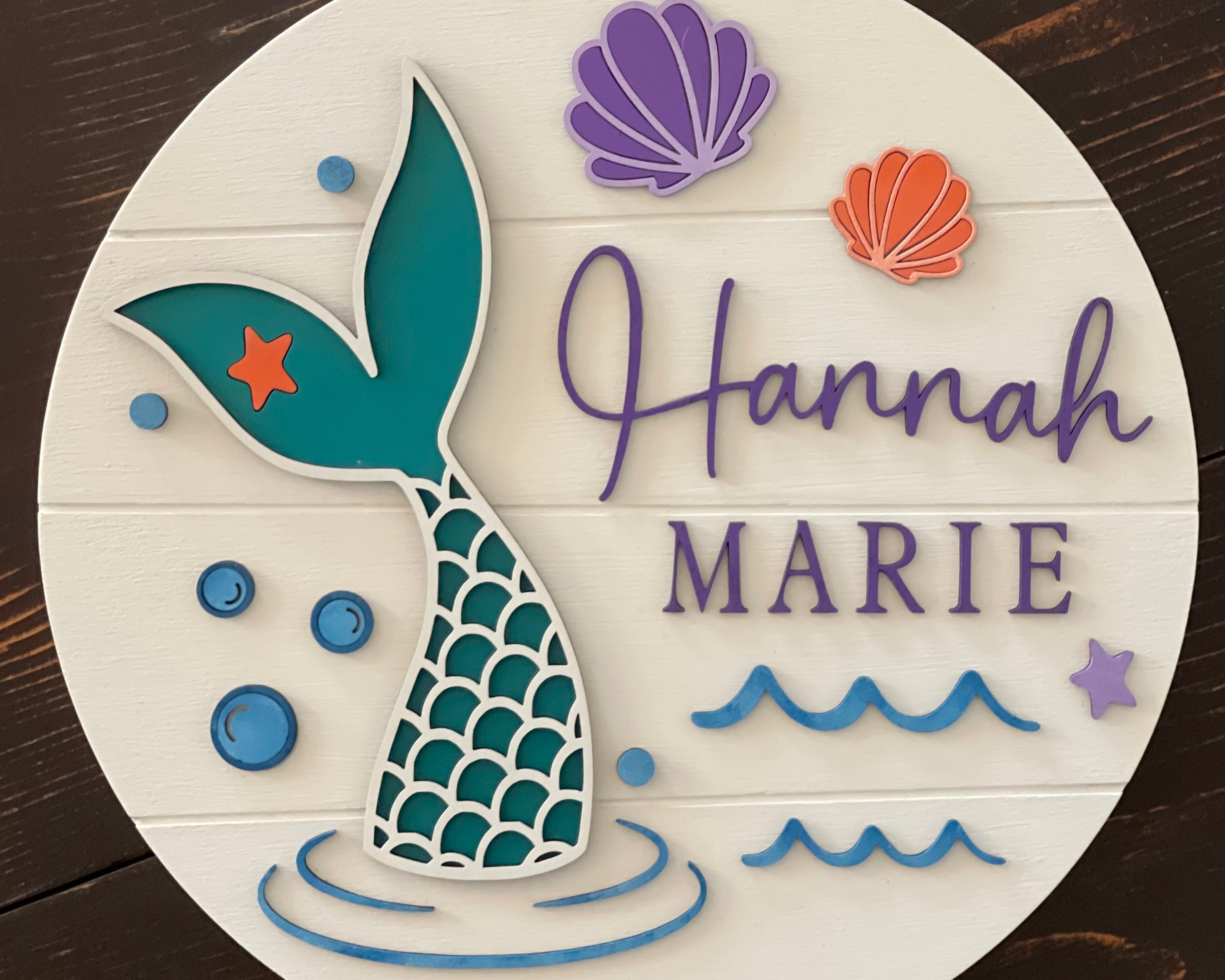 This image shows the mermaid nursery sign displayed on a bench.