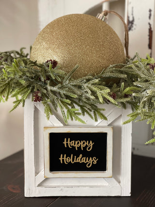 This image shows the Happy Holidays Ornament Box with a gold glitter ornament ball and pine greenery.