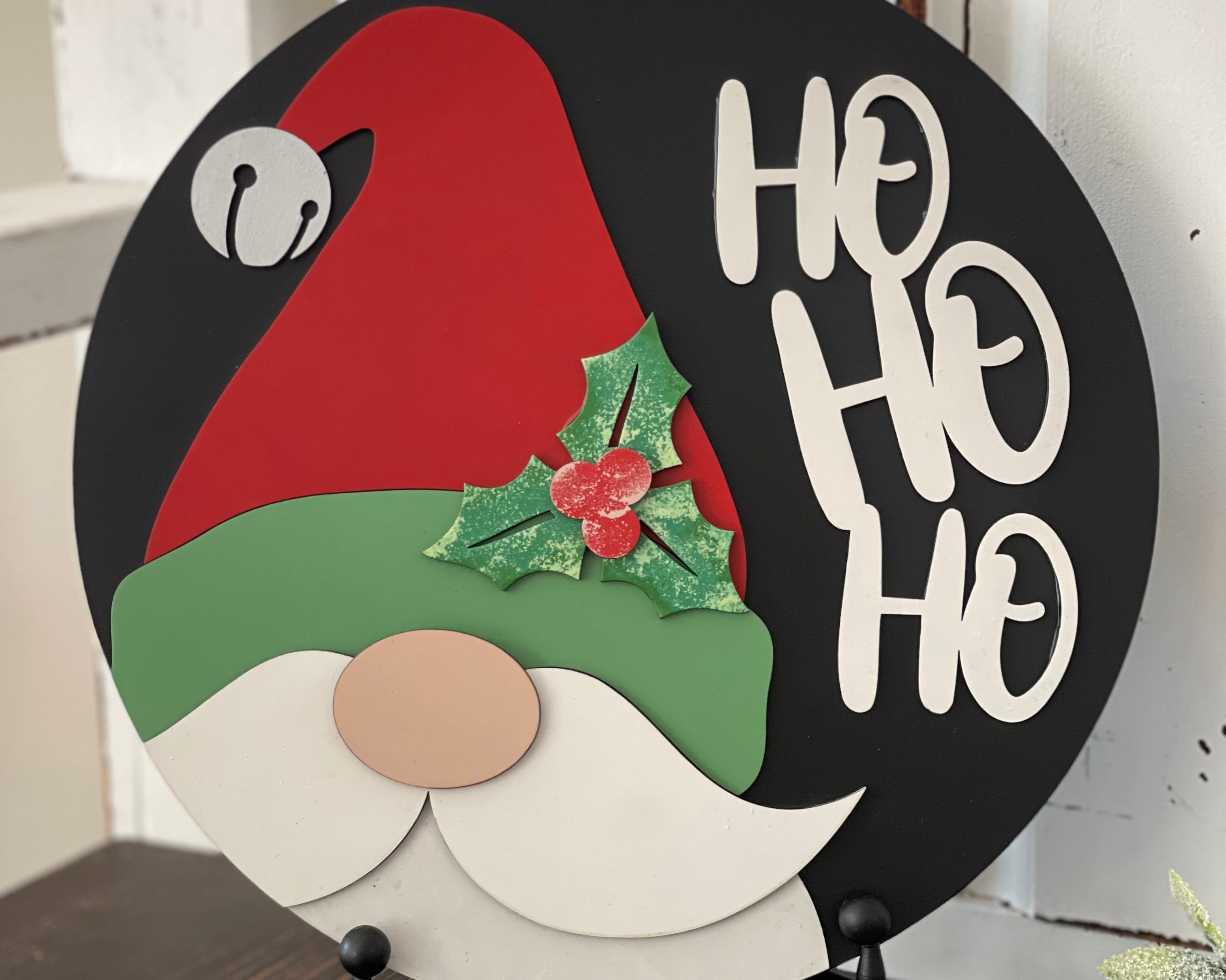 This image shows the hand painted 3D santa sign that reads Ho Ho Ho. The sign is sitting on an easel.