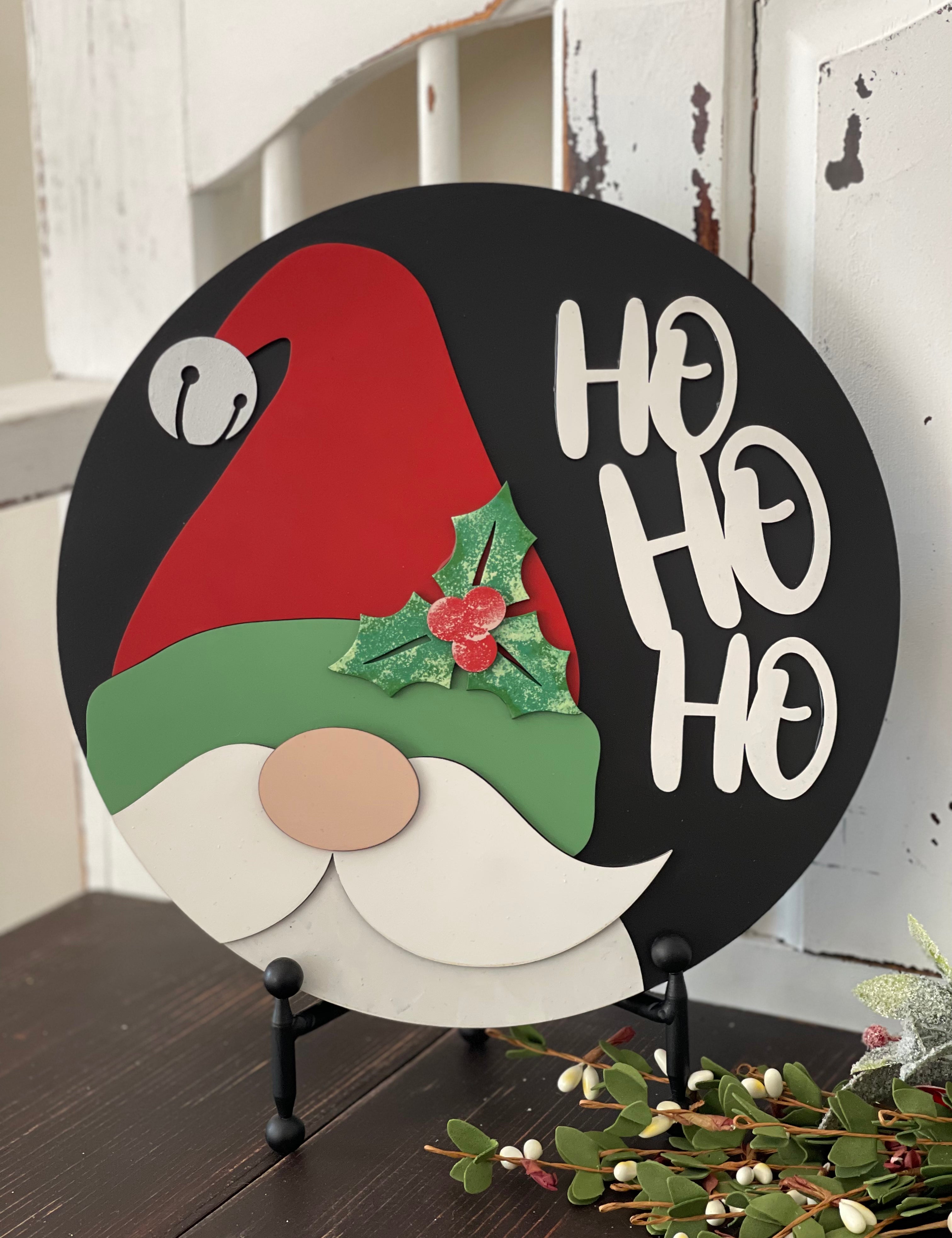 This image shows the hand painted 3D santa sign that reads Ho Ho Ho. The sign is sitting on an easel.