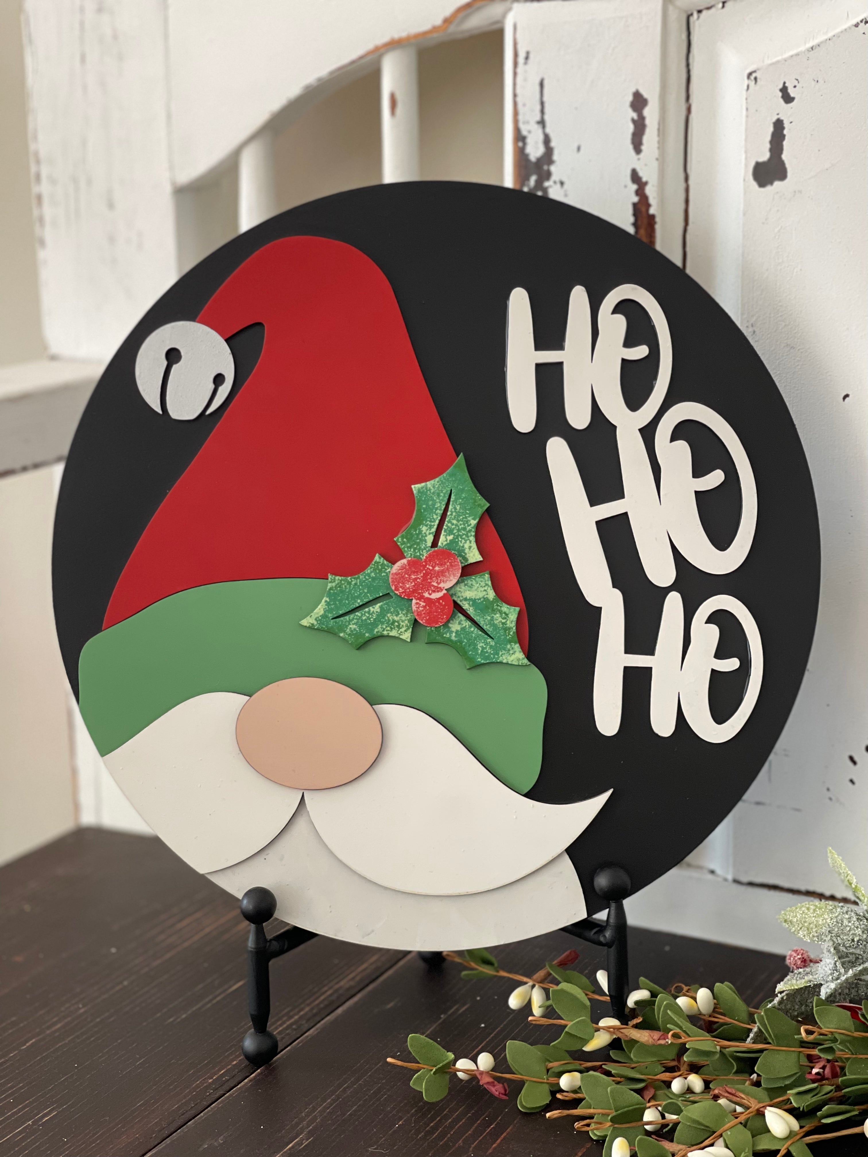 This image shows the hand painted 3D santa sign that reads Ho Ho Ho. The sign is sitting on an easel.