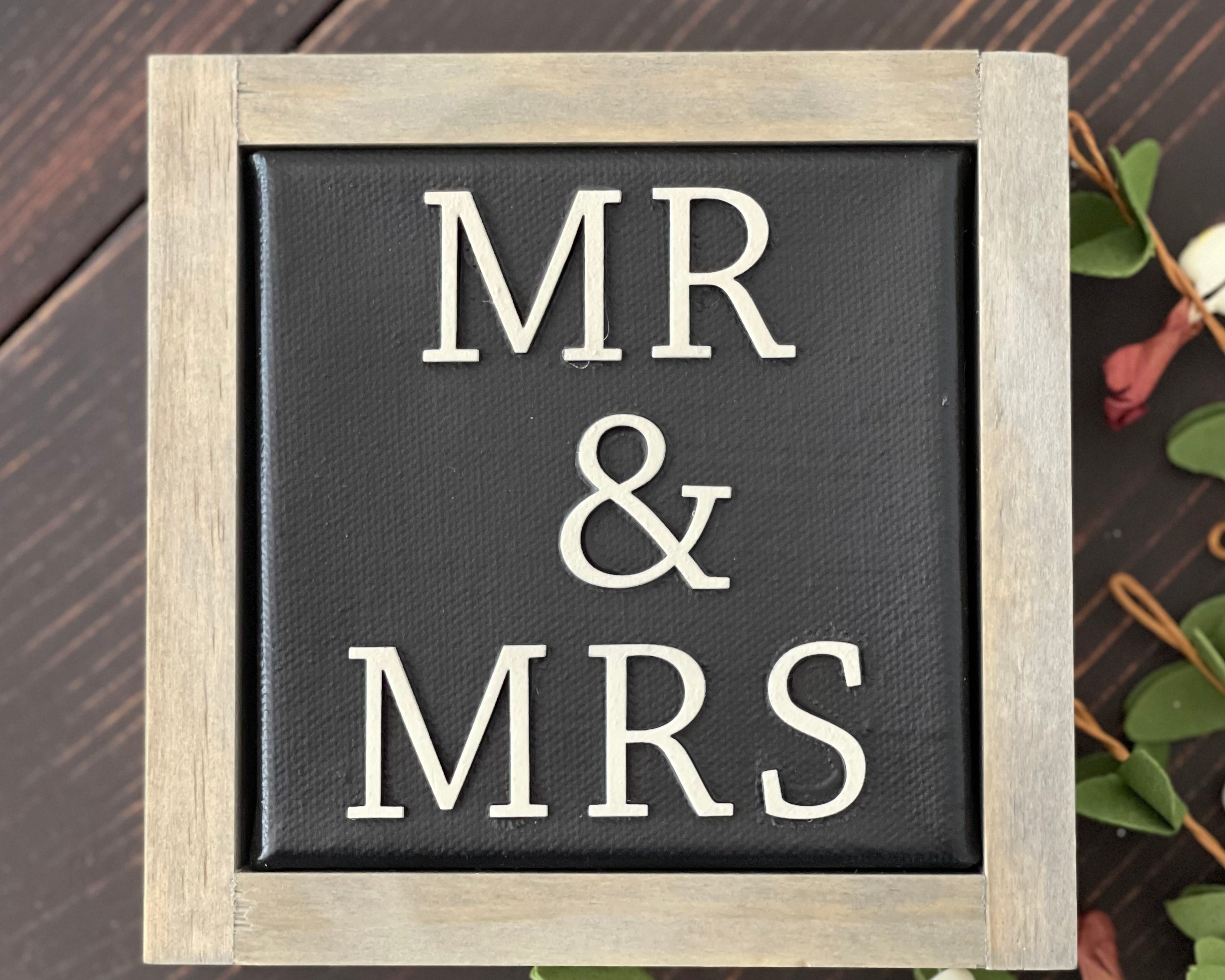Mr + Mrs mini canvas sign is shown displayed on a bench with a floral design.