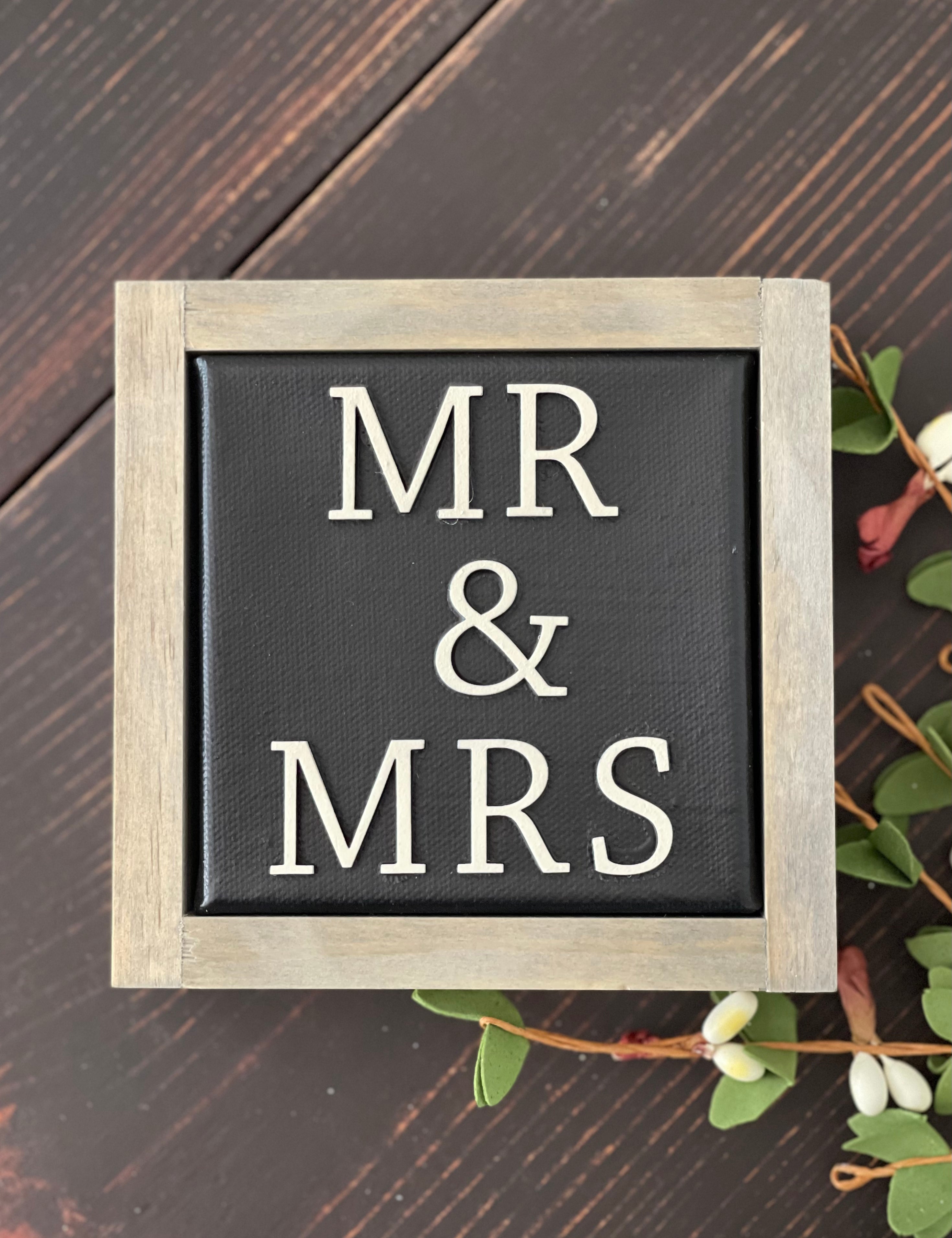 Mr + Mrs mini canvas sign is shown displayed on a bench with a floral design.