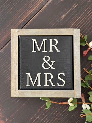 Mr + Mrs mini canvas sign is shown displayed on a bench with a floral design.