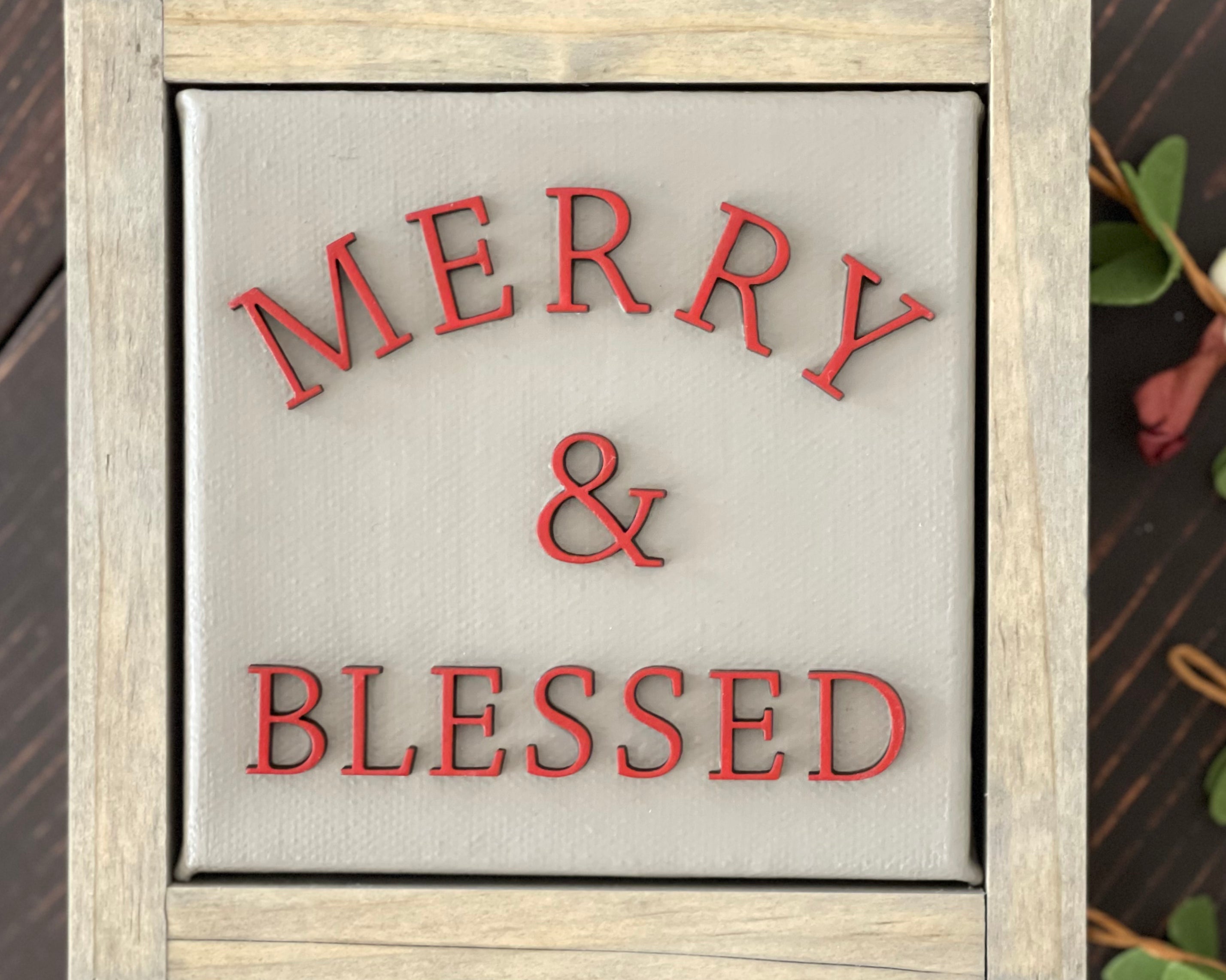 Merry + blessed is displayed on a bench with greenery.