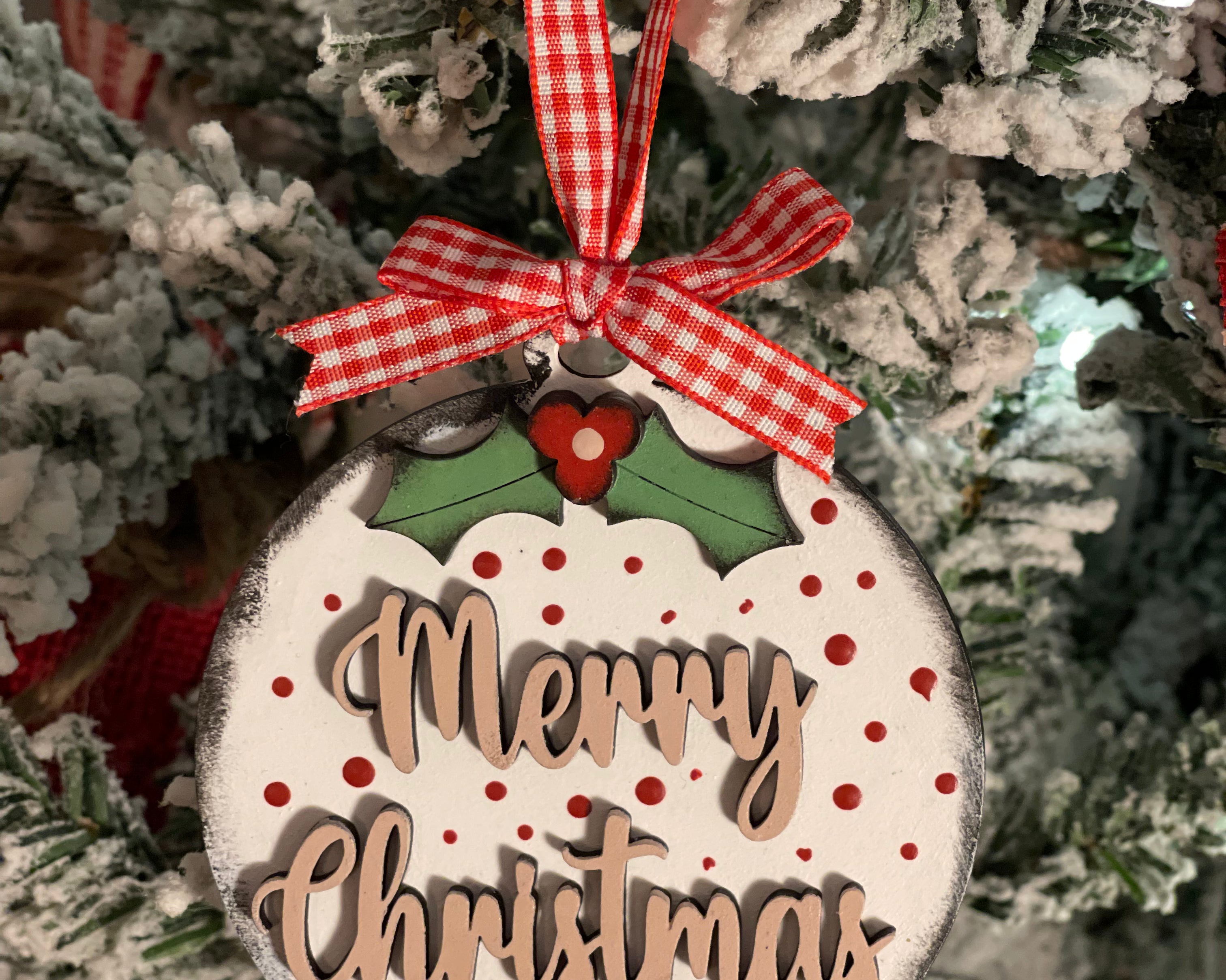 Merry Christmas ornament is displayed hanging on a tree.