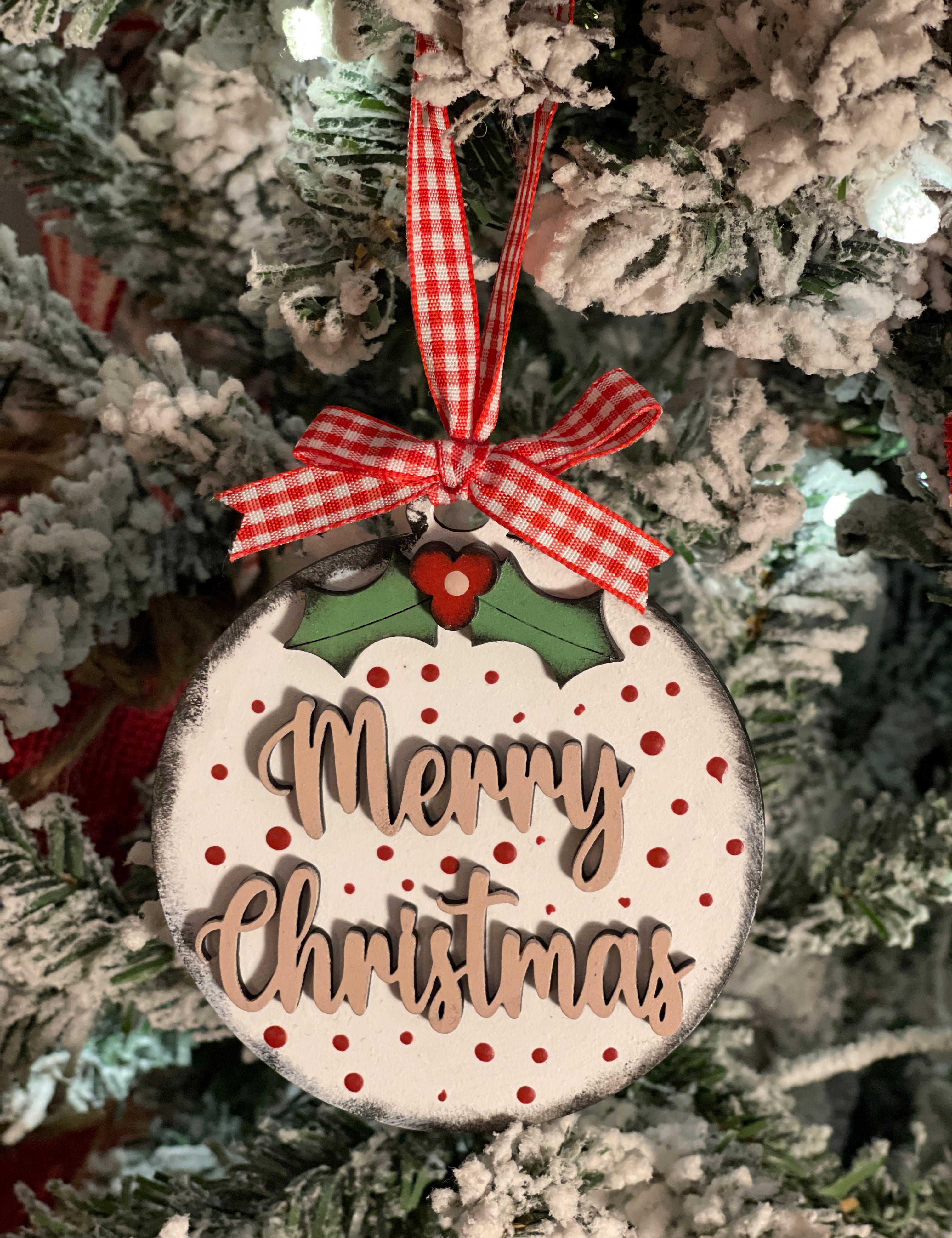 Merry Christmas ornament is displayed hanging on a tree.
