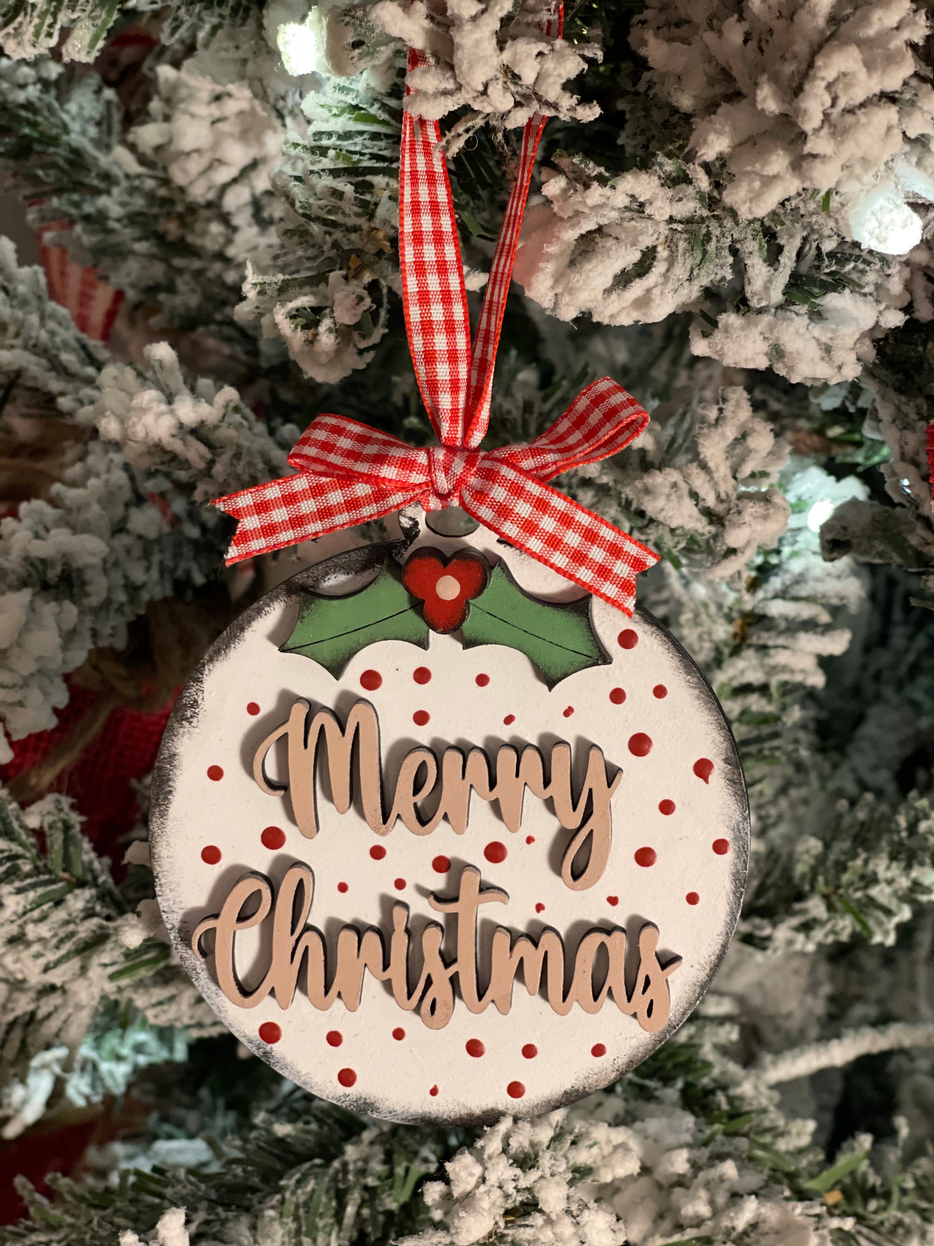 Merry Christmas ornament is displayed hanging on a tree.
