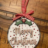 Merry Christmas ornament is displayed on a wood table.