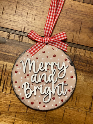 Merry and bright ornament is displayed on a wood table.