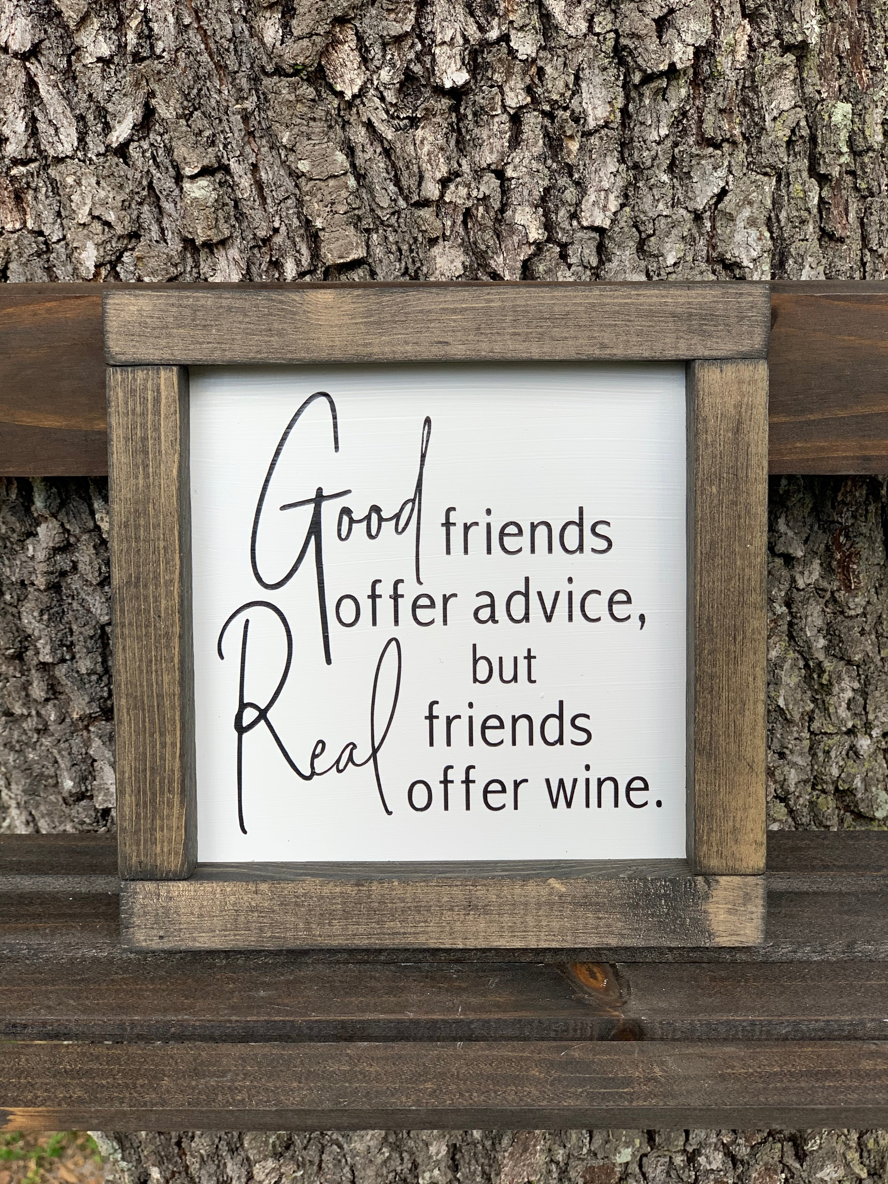 Good Friends Offer Advice, But Real Friends Offer Wine (Script Version) shows the sign sitting outside on a ladder.