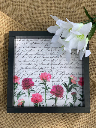 The Vintage Letter is shown laying on a burlap table with a floral stem beside it.