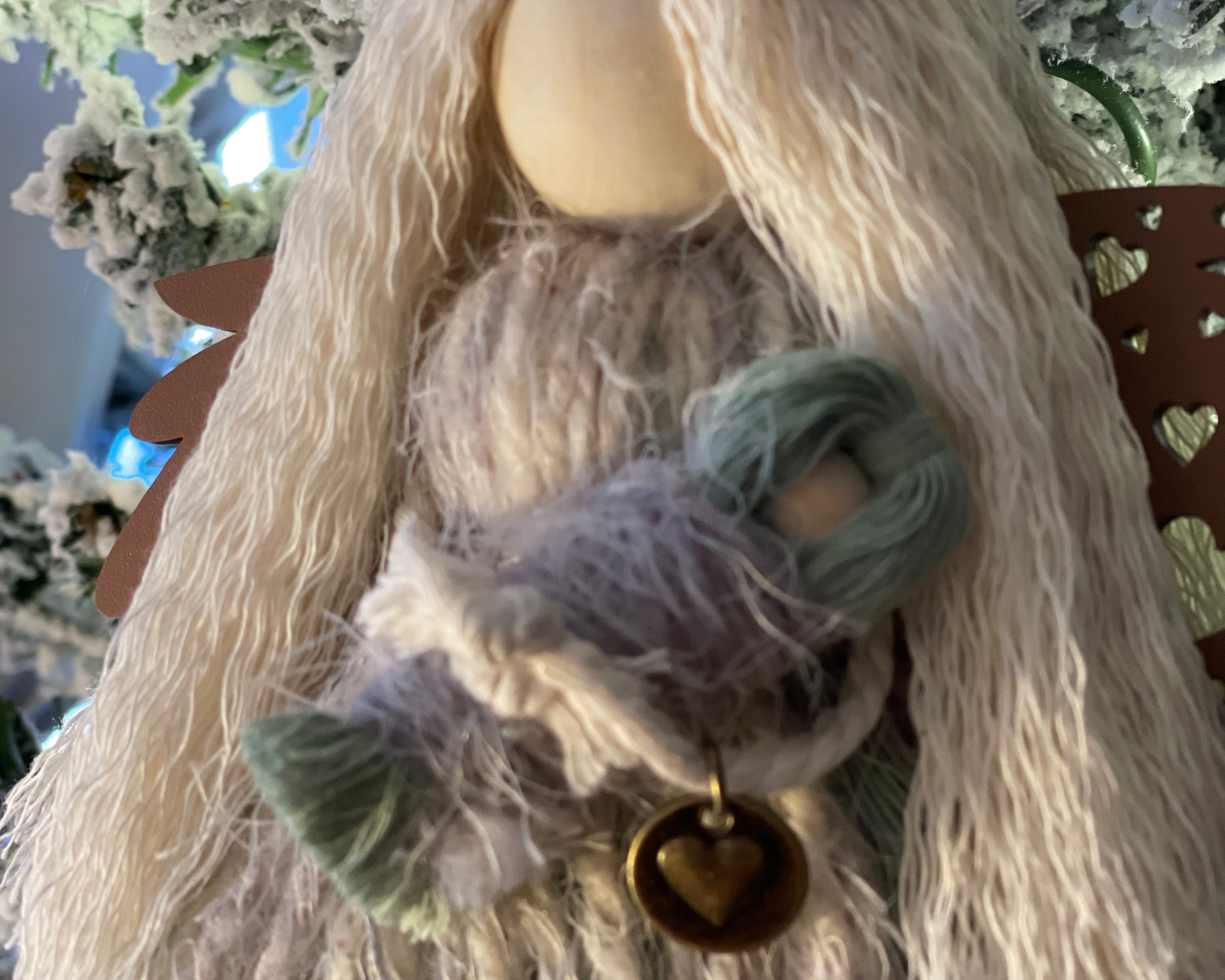 This image shows the agnel close up holding her baby with the heart metal charm embellishment.
