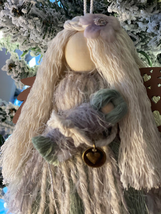 This image shows the agnel close up holding her baby with the heart metal charm embellishment.