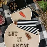 This is the large tan snowman with the saying let it snow in print.