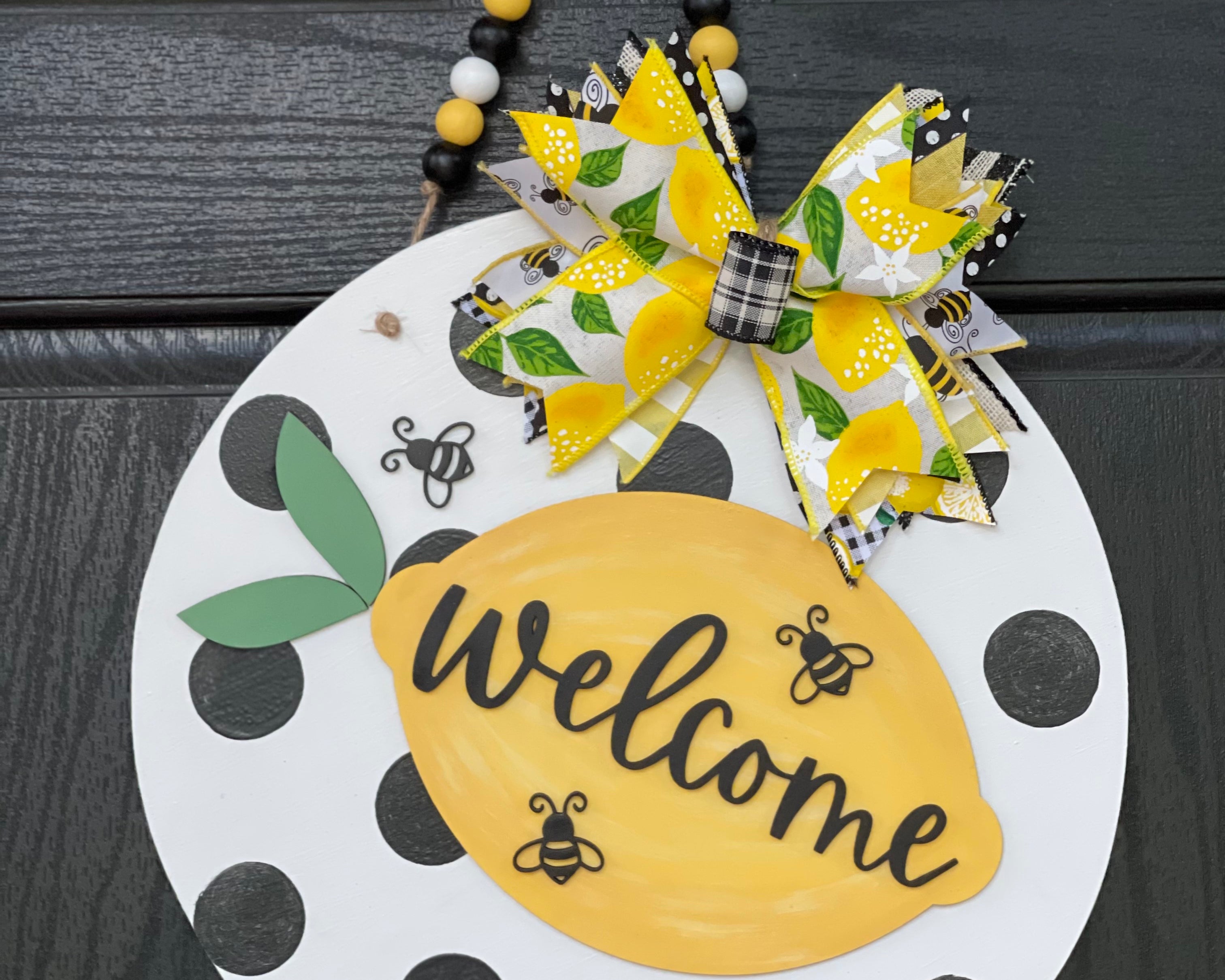 Welcome Lemon Beaded Garland 3D Door or Wall Hanger is shown hanging on a black front door.  The size shown is the 15" round.