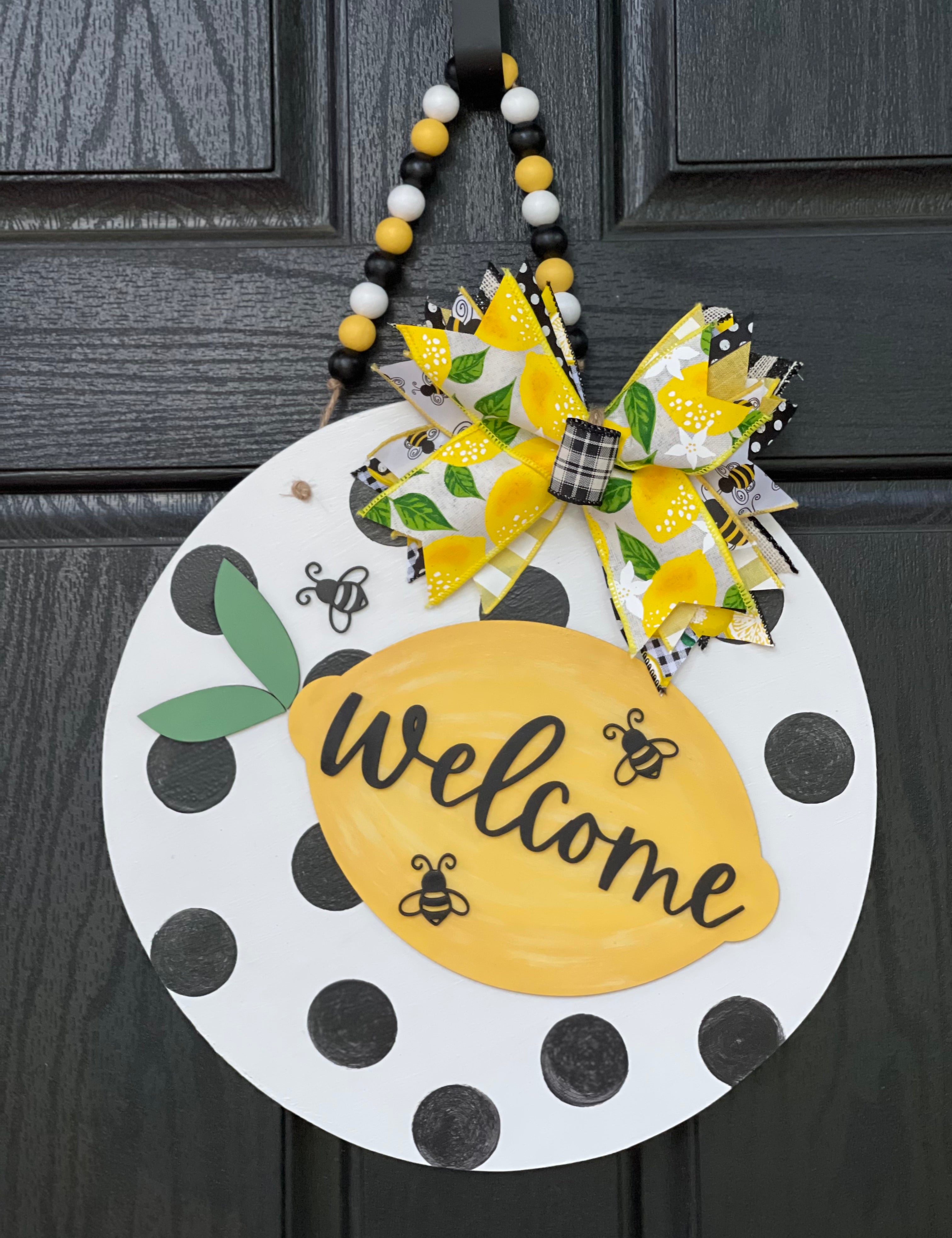 Welcome Lemon Beaded Garland 3D Door or Wall Hanger is shown hanging on a black front door.  The size shown is the 15" round.